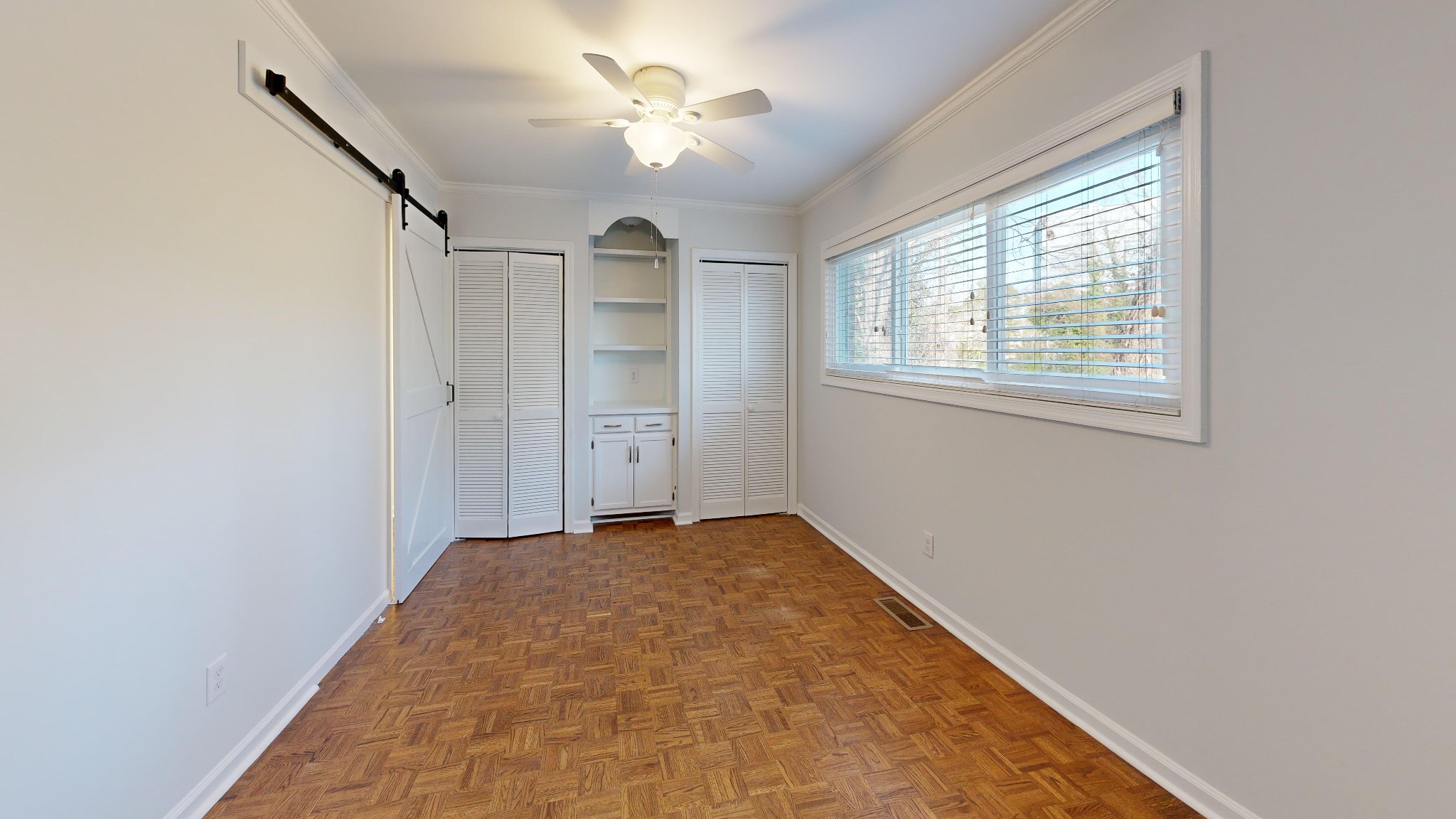 Bedroom with parquet floors and louvered closet doors before renovation in Raleigh townhouse